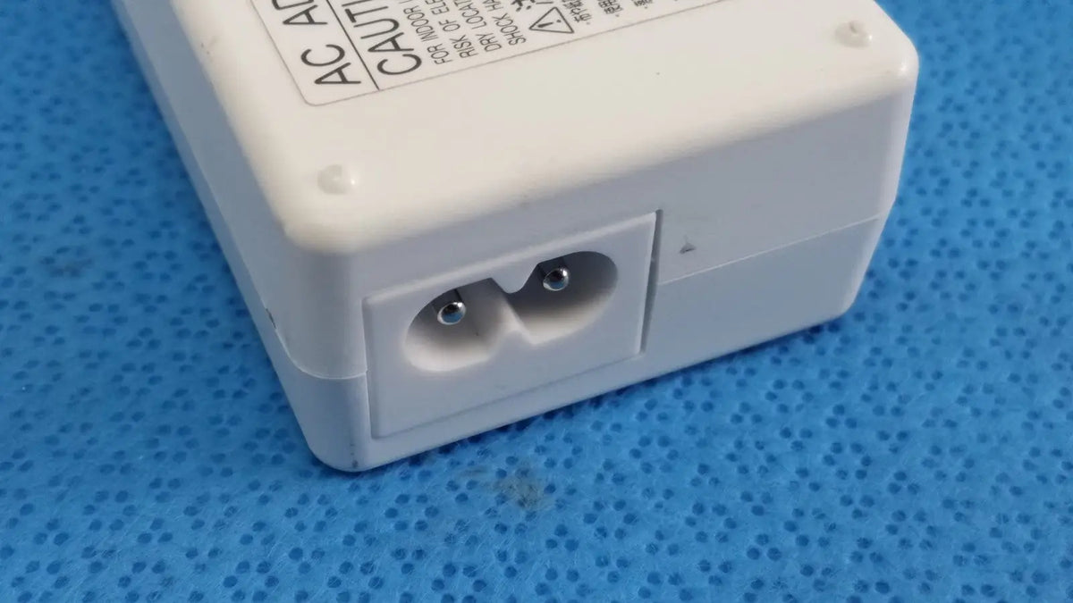 White plastic ac power adapter sed80n2-24 with two round pin sockets and caution label on top surface