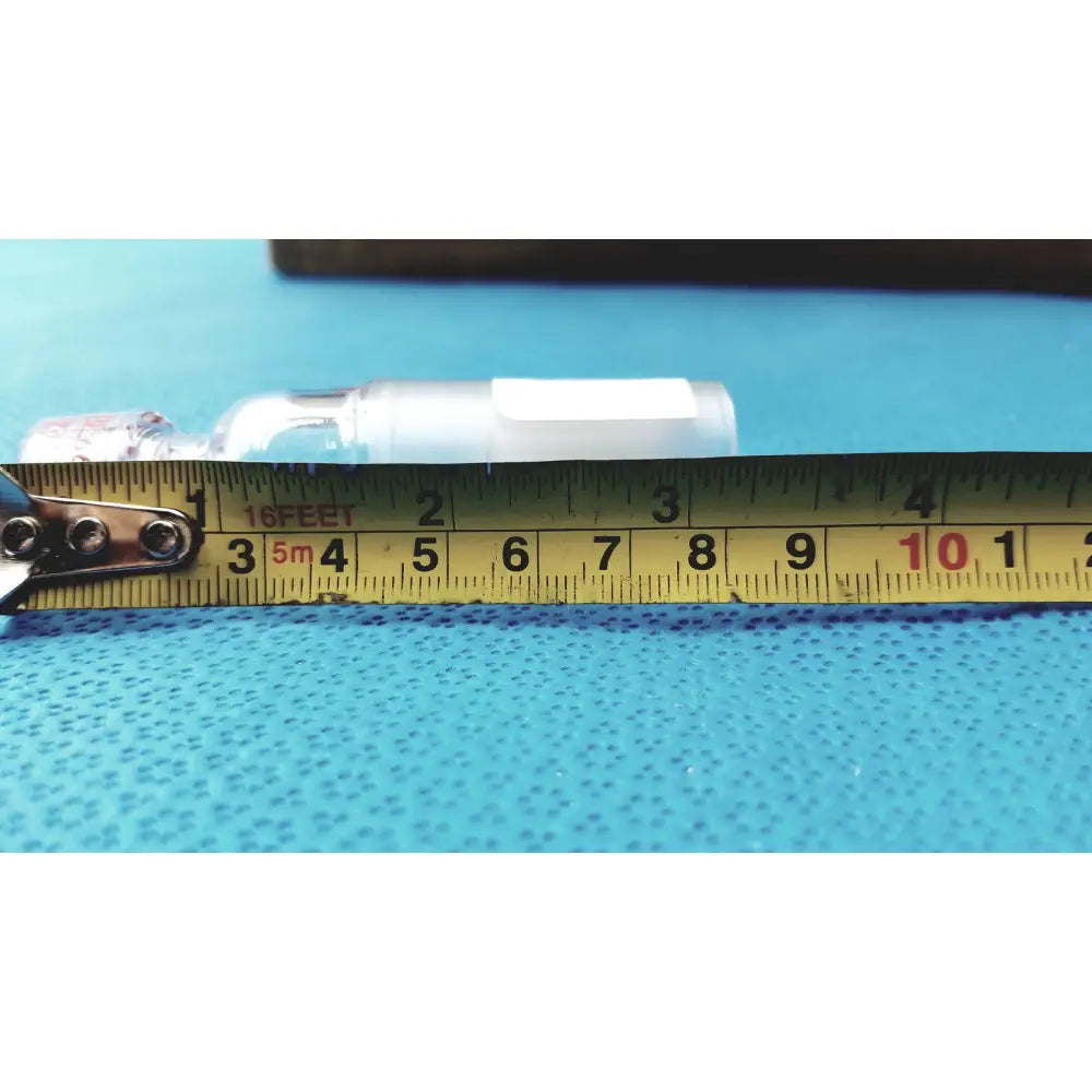 A clear plastic ace glass thermometer adapter with a white cap on a blue surface next to a yellow measuring tape
