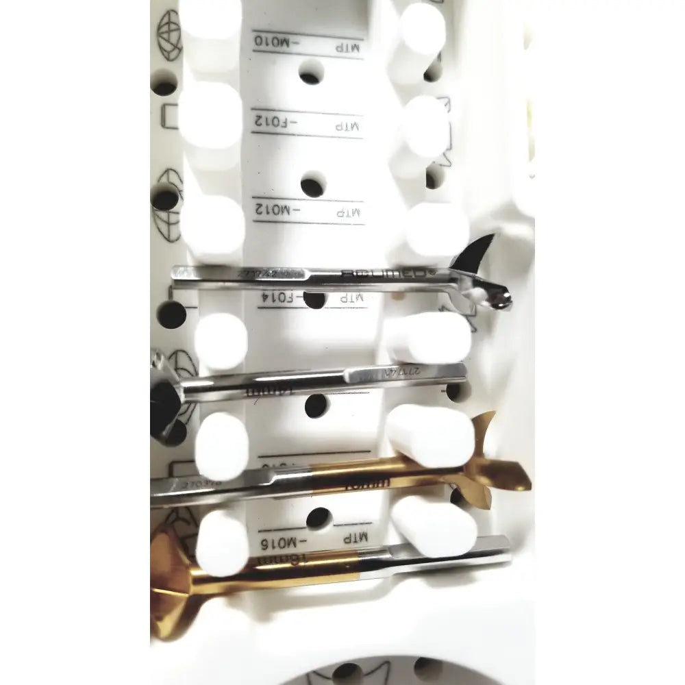 A set of metallic drill bits with black and gold tips in a white foam tray from acumed modular hand system set missing piece
