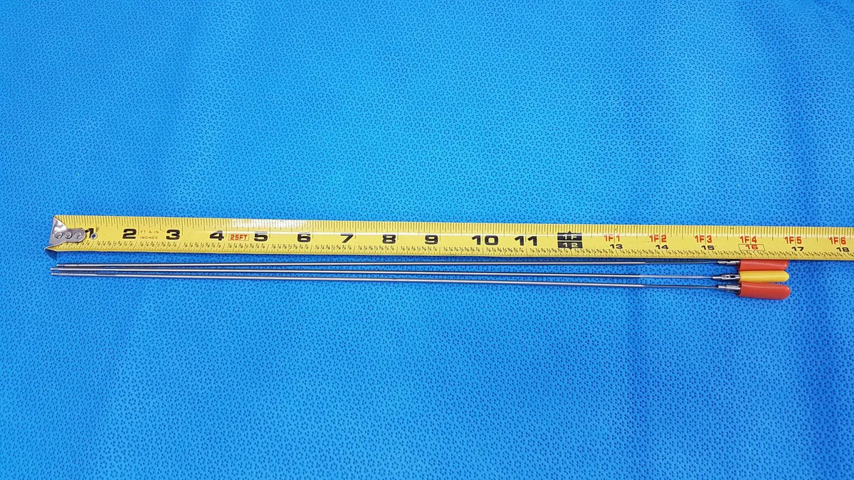 Three slender metallic aesculap laparoscopic instrument needles with orange and yellow handles and measuring tape for reuse medical use