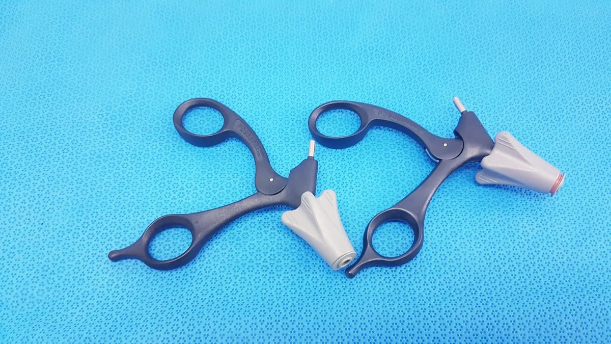 Black Aesculap p0958r quick snap non-ratchet laparoscopic scissors with white cone-shaped tips on blue surface