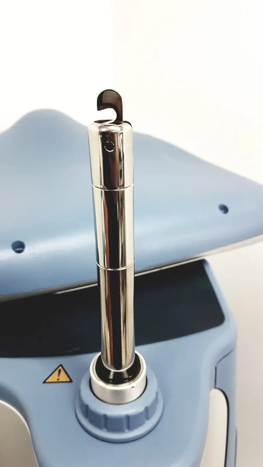 Shiny chrome cylindrical rod with curved hook on light blue base of alcon infiniti vision phacoemulsification unit