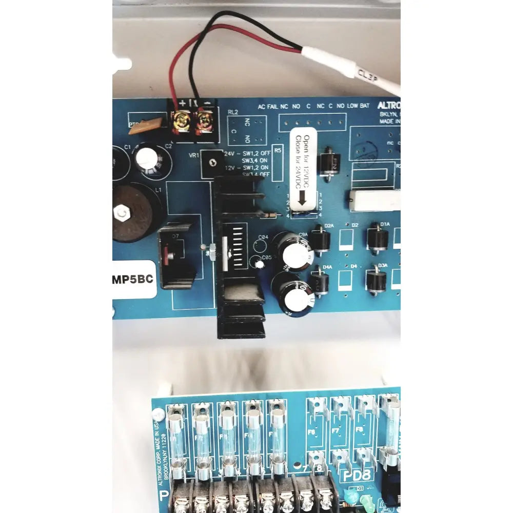 Blue circuit board with switches capacitors and wiring in altronix smp5ctx power supply charger for 12vdc or 24vdc