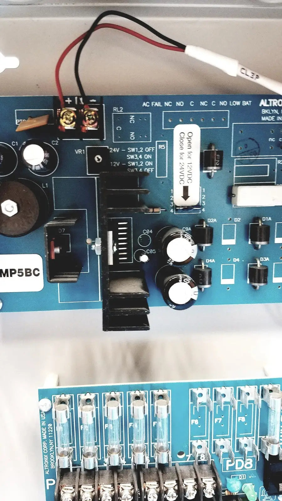 Blue circuit board with switches capacitors and wiring in altronix smp5ctx power supply charger for 12vdc or 24vdc