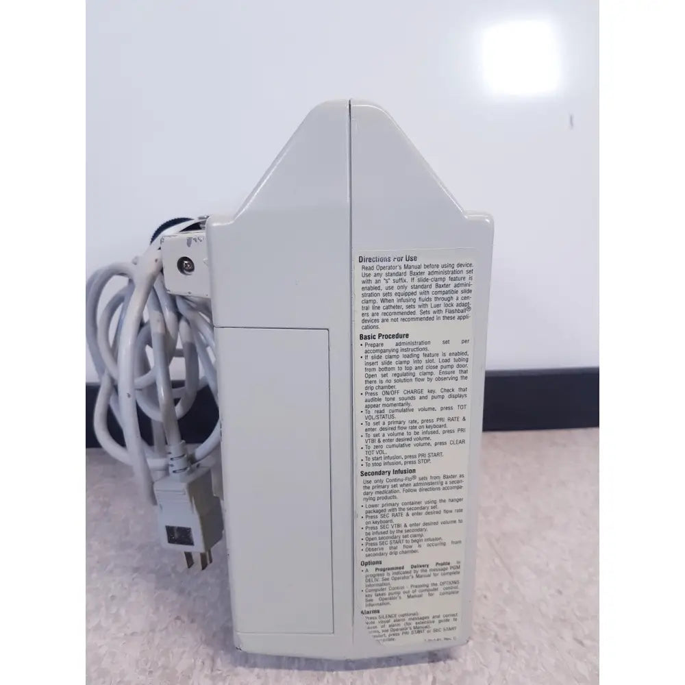 White plastic baxter 2m8063 volumetric infusion pump with printed instructions and labels for medical use