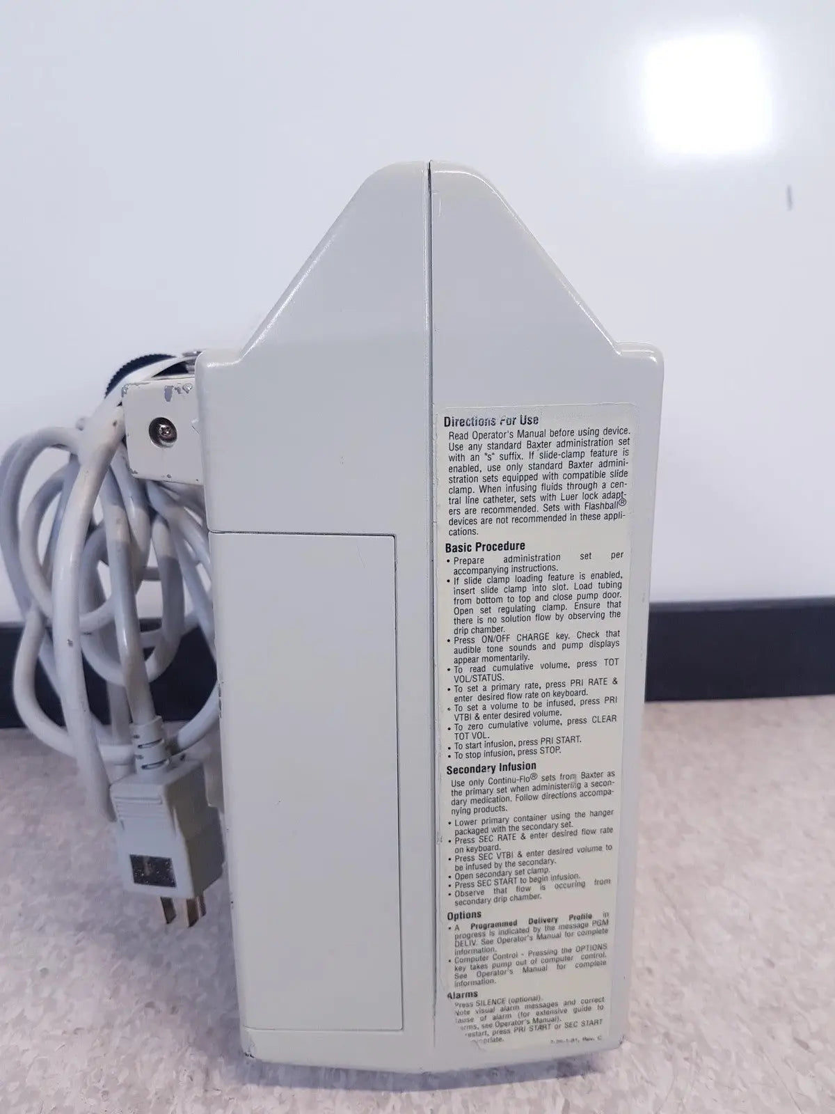 White plastic baxter 2m8063 volumetric infusion pump with printed instructions and labels for medical use