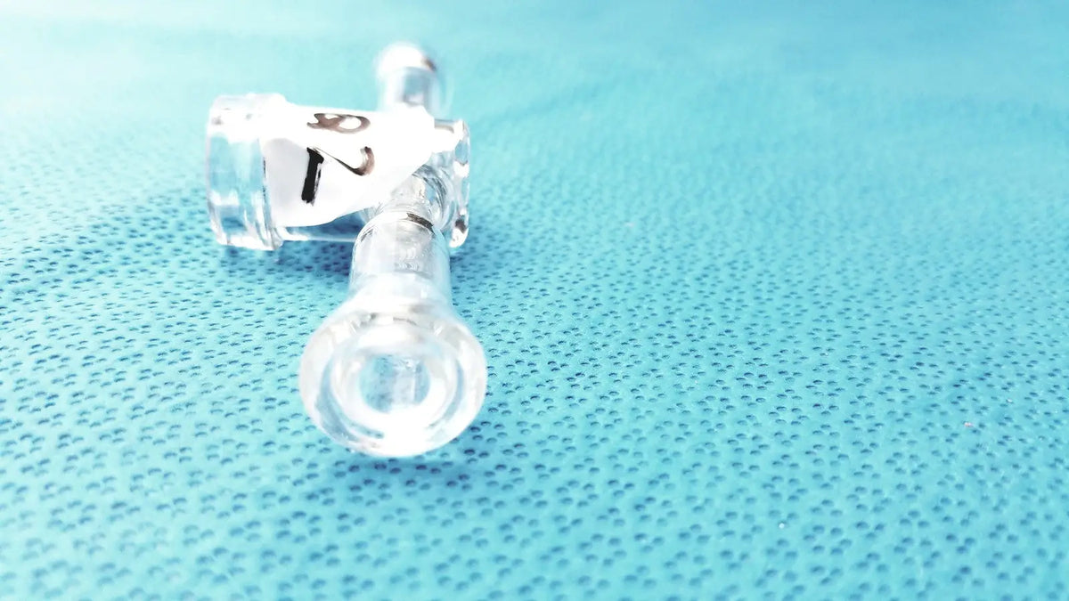 Clear plastic medical tubing with labeled connectors attached to a borosilicate glass stopcock adapter lab valve connector 24/40 joint