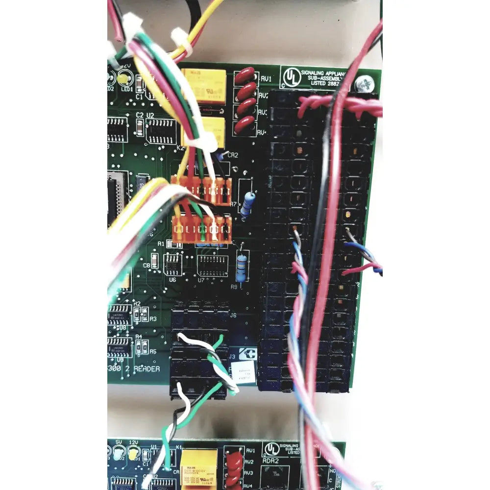 Green circuit board of cardkey s300-xl access control panel controller with red black switches yellow capacitors and wires