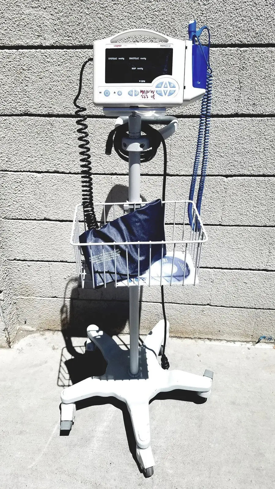 White casmed 740 vital signs monitor on wheeled stand with wire basket and blue tubing for medical use