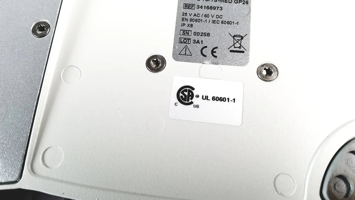 White plastic backplate of cellvizio foot pedal with silver screws and regulatory compliance labels visible