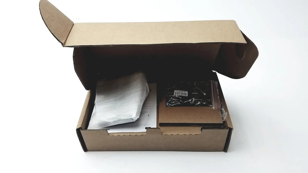 Brown cardboard box with flaps open containing wrapped cisco ip phone key expansion module and black plastic bag