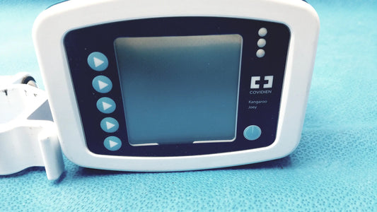 White plastic Covidien kangaroo joey enteral flush pump with black screen blue buttons and pole clamp attachment