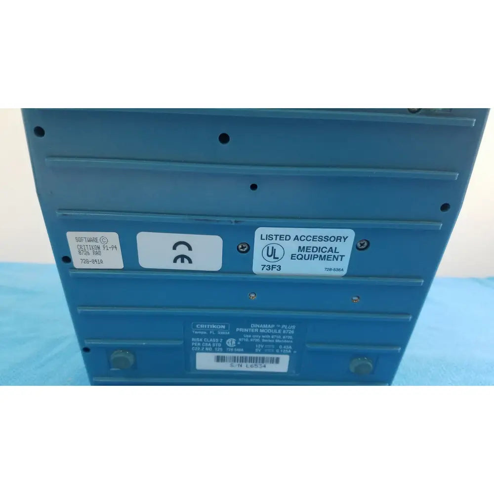 Blue plastic printer module with labels and certification stickers on back of critikon dinamap plus vital signs monitor 8726 rad