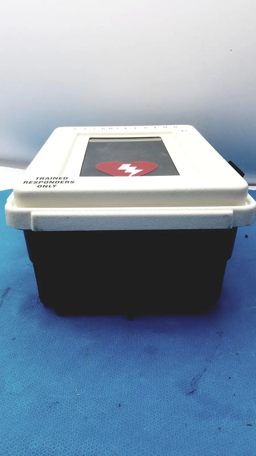 Defibrillator storage cabinet wall mount in white and black with a red heart symbol on the screen for emergency use
