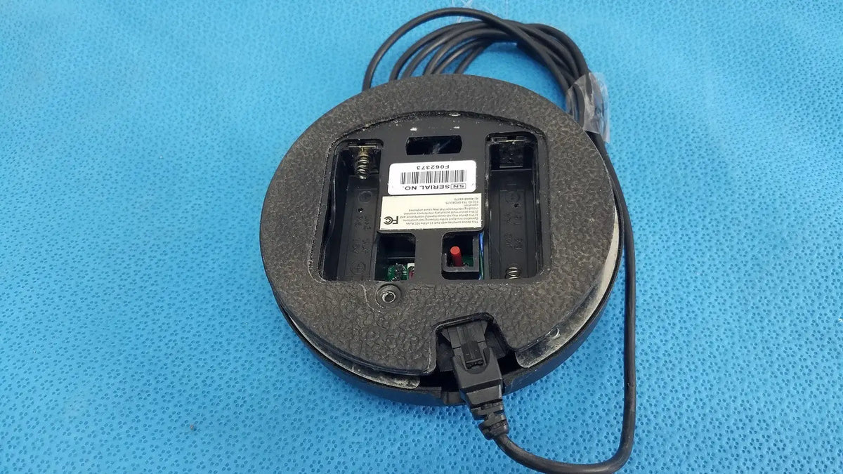 Black dentsply cavitron foot control mouse with textured rubber surface and visible battery compartment plugged in