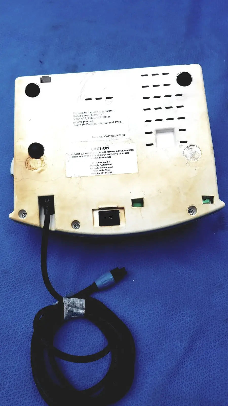 White plastic dentsply cavitron plus ultrasonic scaling unit with black power cord and connector shown from the back side