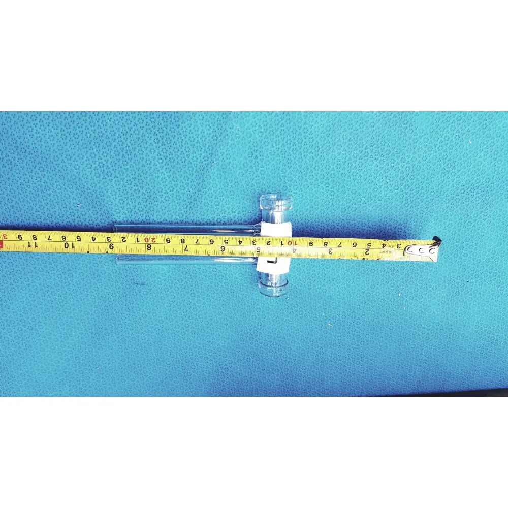 Clear glass double oblique bore glass stopcock with white clamps on yellow measuring tape made of borosilicate