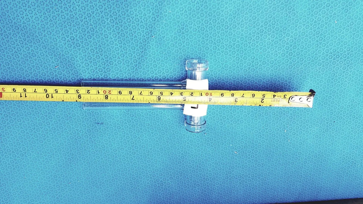 Clear glass double oblique bore glass stopcock with white clamps on yellow measuring tape made of borosilicate