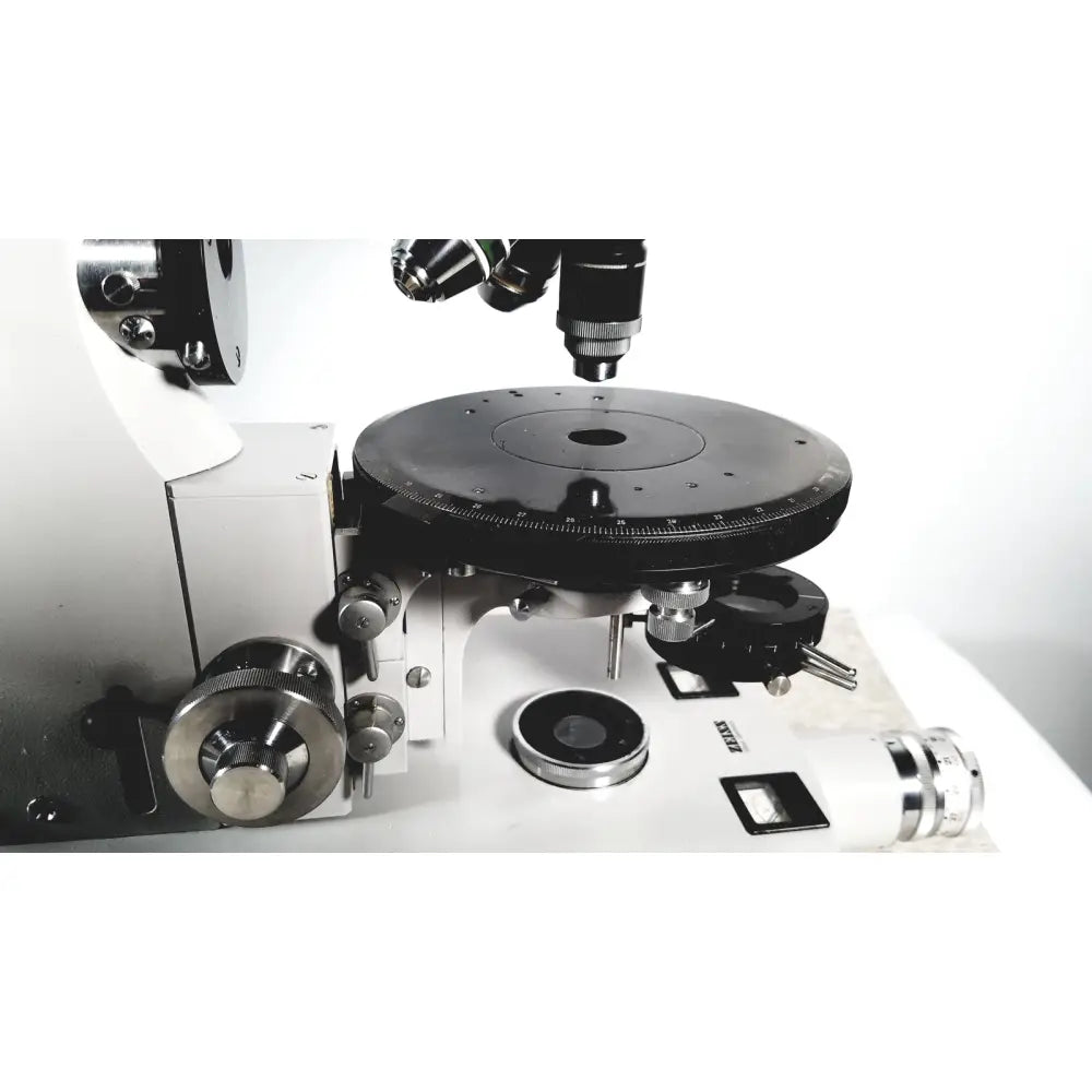 Black and silver compound microscope with rotating stage and lenses shown with eppendorf centriifuge 5415 R for reuse medical applications