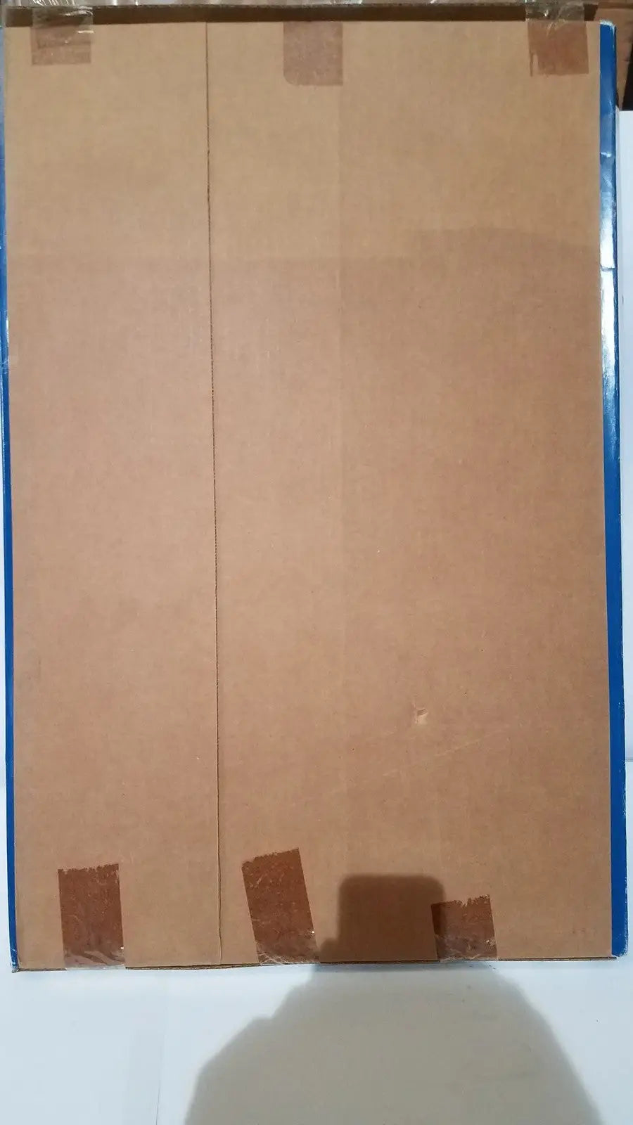 Two brown cardboard panels taped together representing the back side of the freedom grip plus bed handle patient support aid