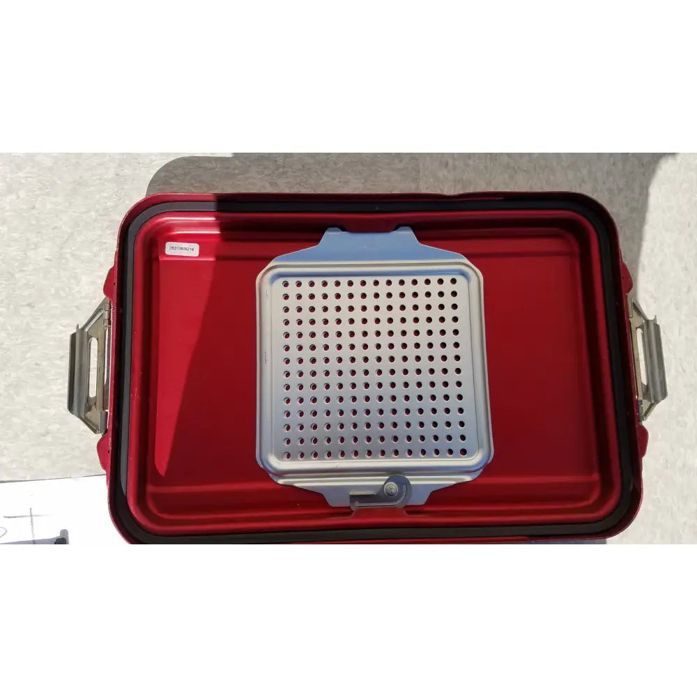 Silver perforated grill grate resting inside red genesis sterilization container half lid for secure sterilization storage