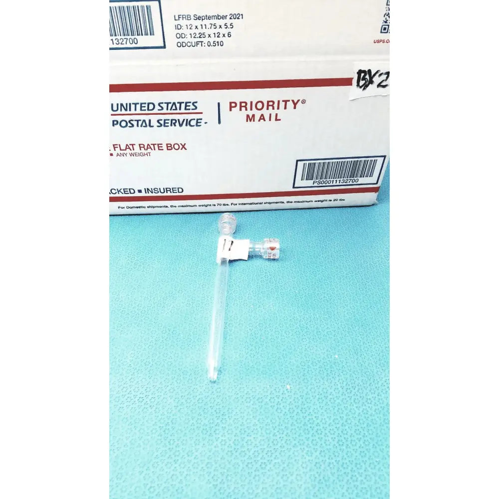 Clear plastic medical syringe with white plunger on blue surface next to glass schlenk storage tube with high vacuum ptfe valve