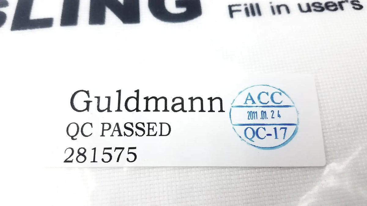White rectangular label on guldmann disposable micro plus sling max 250kg with black text and a blue quality control stamp