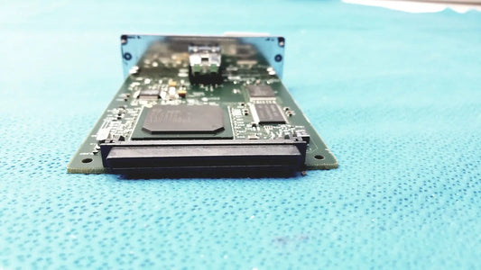Green circuit board with black components and silver metal bracket of hp jetdirect 620n fast ethernet print server