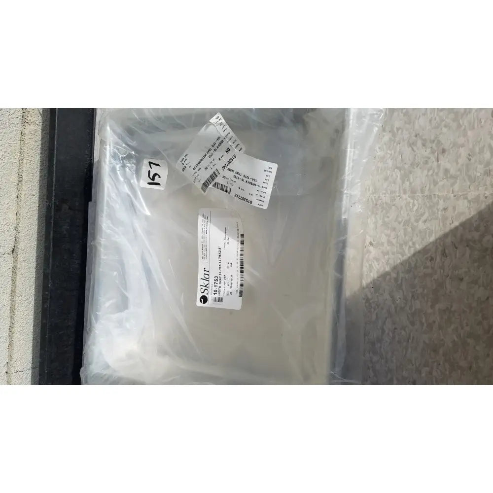 A clear plastic bag containing a sklar instrument tray solid reuse medical sterilization tray with labels and barcode visible