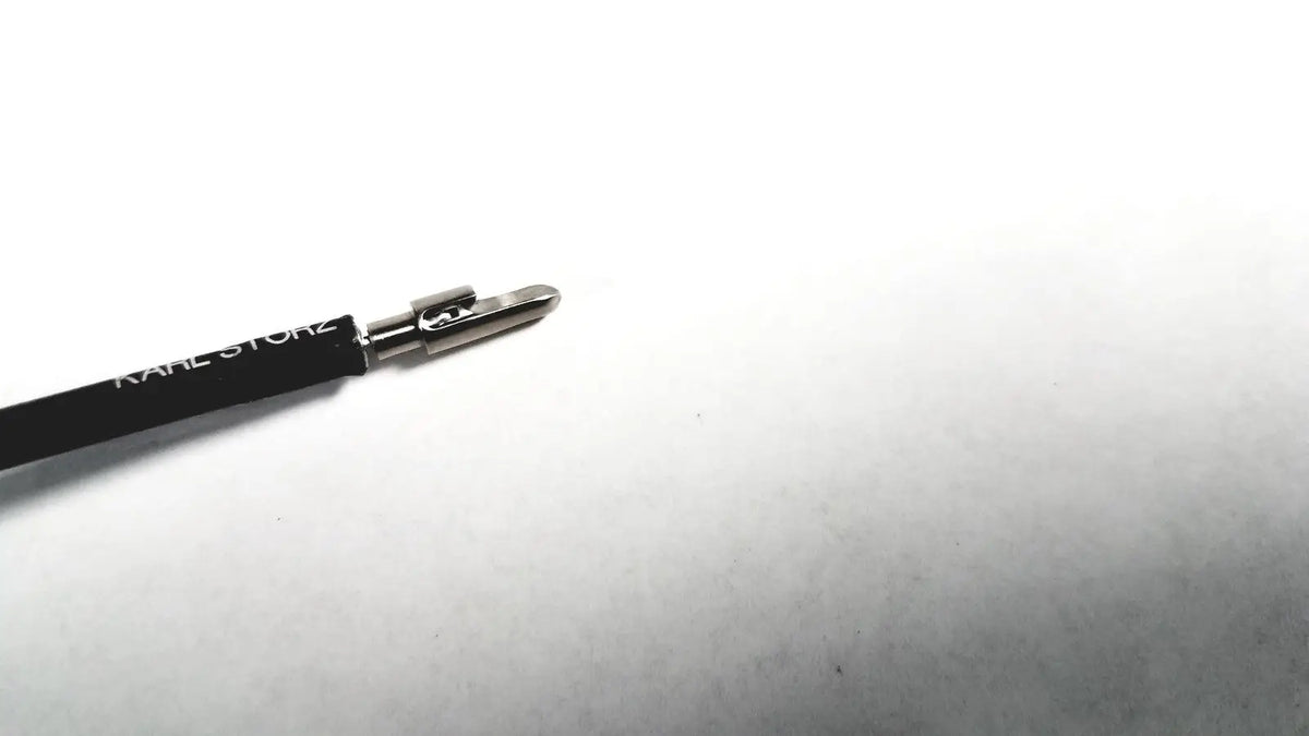 Black karl lagerfeld eyeliner pencil with silver metallic tip and logo next to karl storz clickline metal handle laparoscopic tool