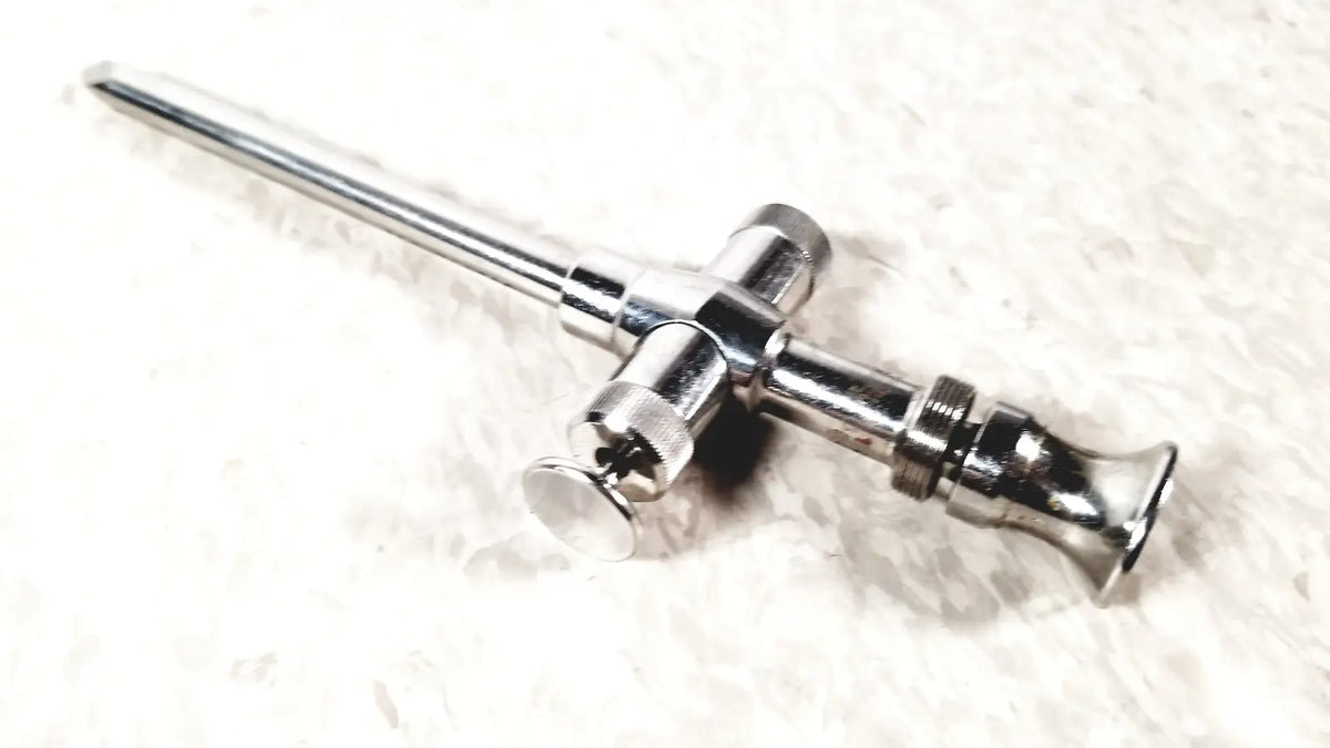 Shiny chrome reusable metal trocar sleeve with long slender shaft and cross-shaped handle featuring threaded sections