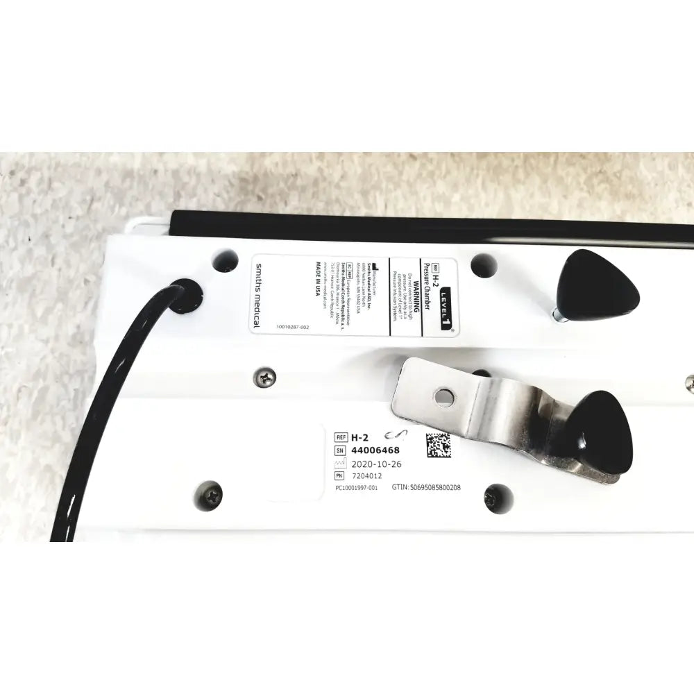 White plastic smiths medical model h-2 pressure chamber with black triangular knobs and metallic clamp for pressure control