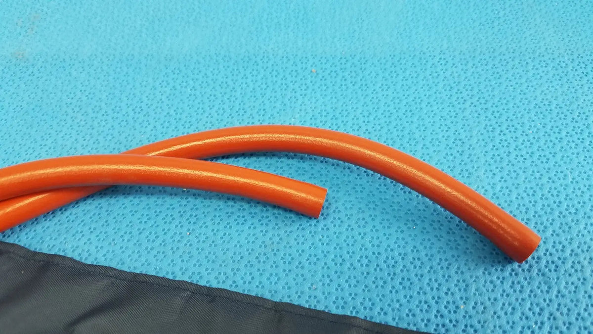 Orange flexible tubing of medline sphygmomanometer artery large blood pressure cuff rests on a blue textured surface