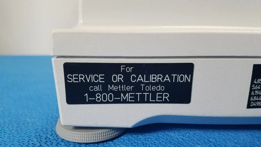 White laboratory balance with black label for service or calibration call mettler toledo 1-800-mettler with silver knobs for xp5003sdr