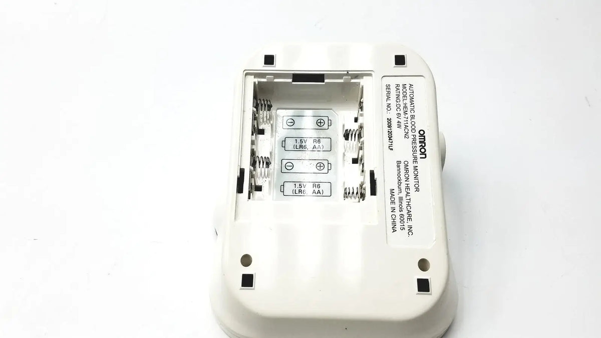 White plastic omron advanced blood pressure monitor hem-711ac showing battery compartment and labeled specifications