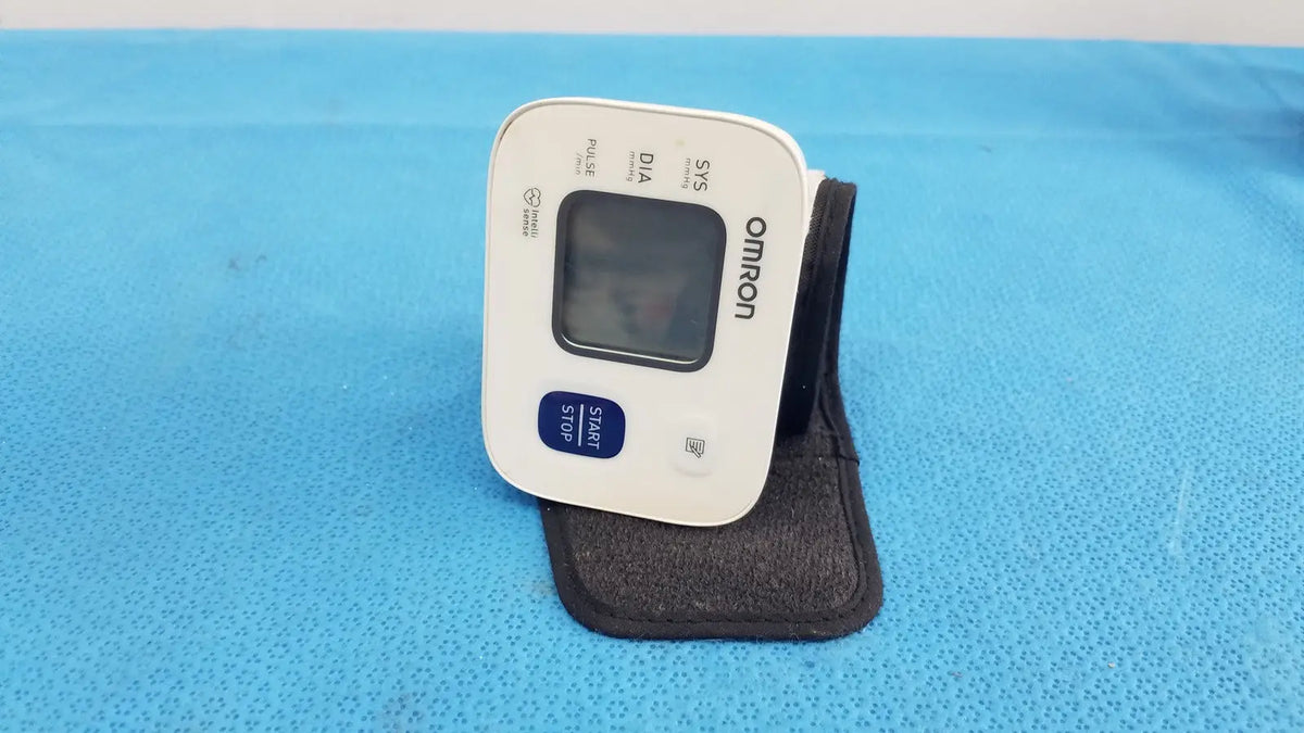 White omron automatic wrist blood pressure monitor with digital display and blue start stop button for accurate readings