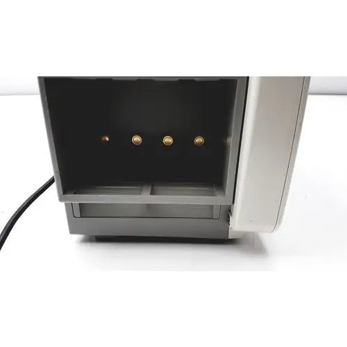 Gray plastic cash register with four gold-colored coin slots shown with philips intellivue mp50 patient monitor A