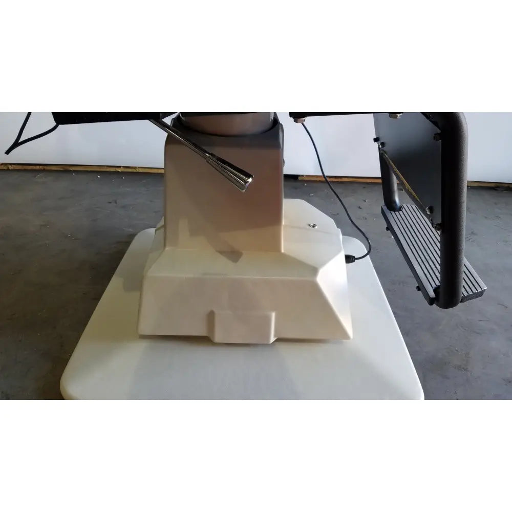 Cream-colored plastic base with metallic lever and black metal arm on reliance medical products model 6100 exam chair