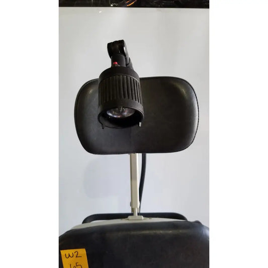 Black adjustable headrest-mounted lamp with ribbed housing and articulated arm on reliance medical products model 6100 exam chair