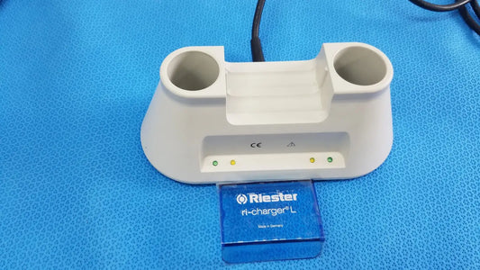 White plastic riester ri-charger l charging base with two circular slots and indicator lights for reuse medical devices