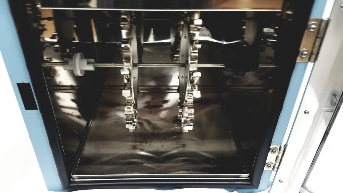 Industrial-grade stainless steel gear assembly inside blue and white chamber of robbins scientific hybridization incubator model 400