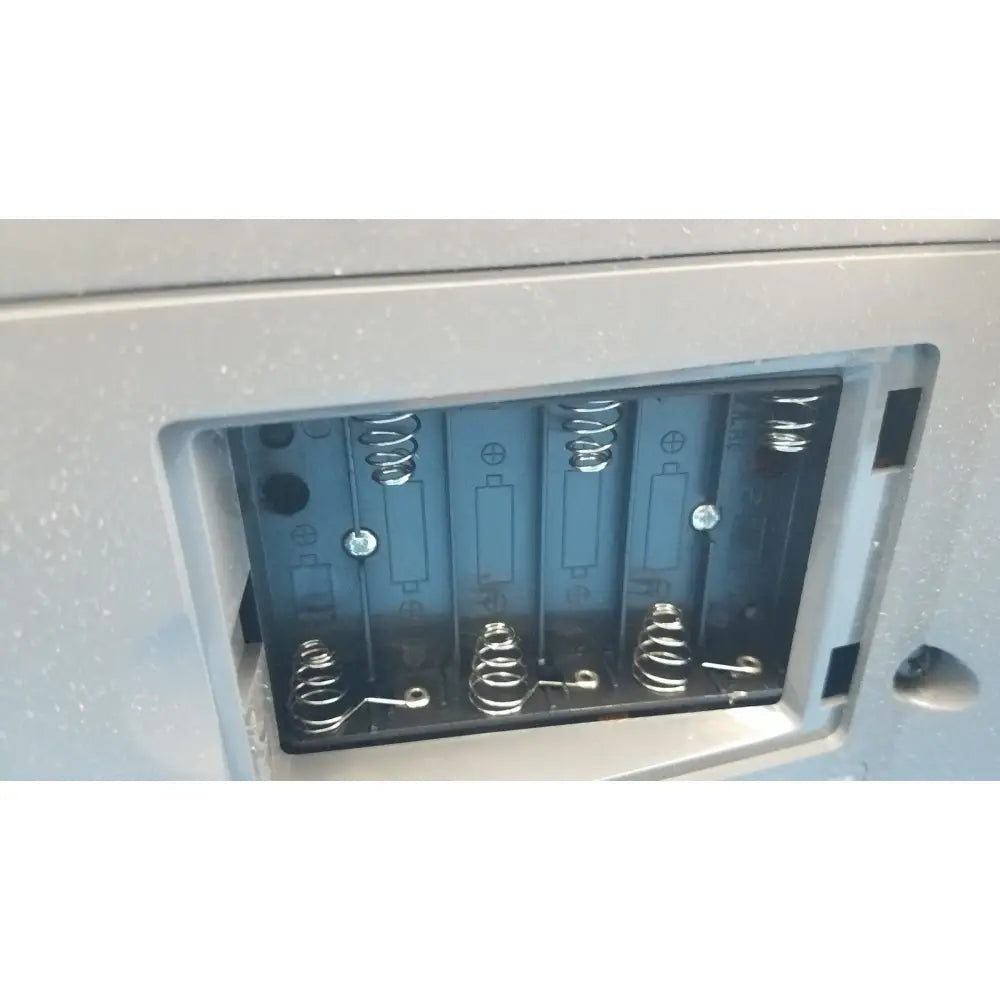 Gray plastic battery compartment with four metal springs for AA batteries on the back of Siemens Healthcare Clinitek Status analyzer