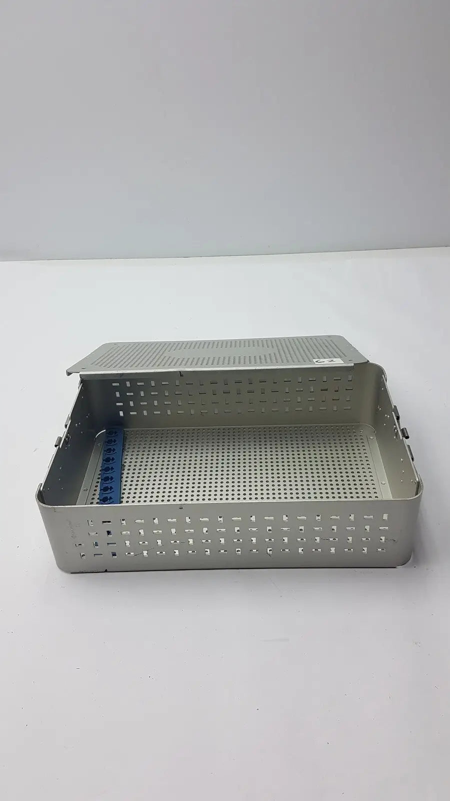 Solid brass sterilization storage container with silver perforated metal tray hinged lid and blue plastic divider