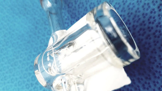 Clear glass bong with curved bowl and metallic accents featuring a spherical joint glass stopcock valve adapter