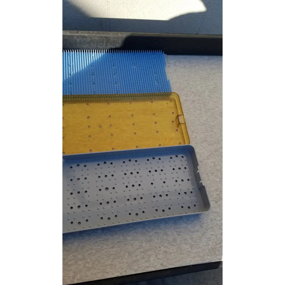 Blue yellow and gray plastic perforated surgical instrument trays designed as sterilization basket trays for stainless steel use
