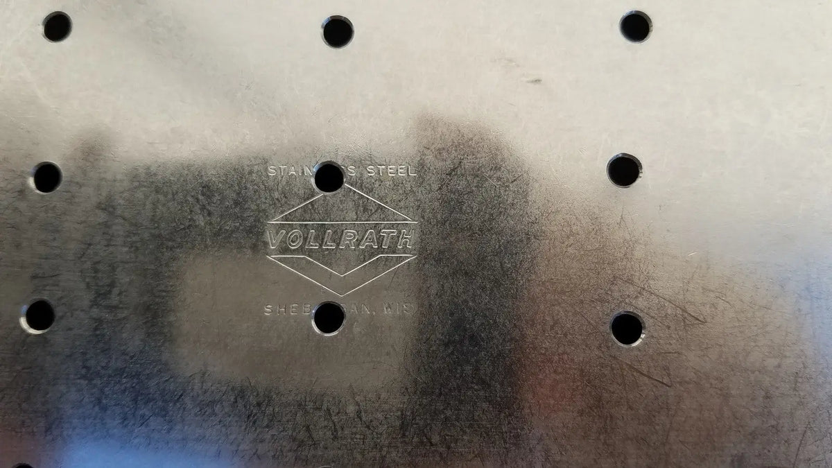 Stainless steel vollrath colander with embossed logo and evenly spaced holes for vollrath sheboygan tray use