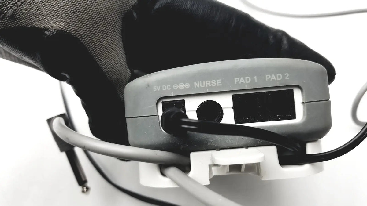 Gray plastic stanley healthcare m200 nurse call unit backside showing labeled ports for nurse and patient pads connectivity