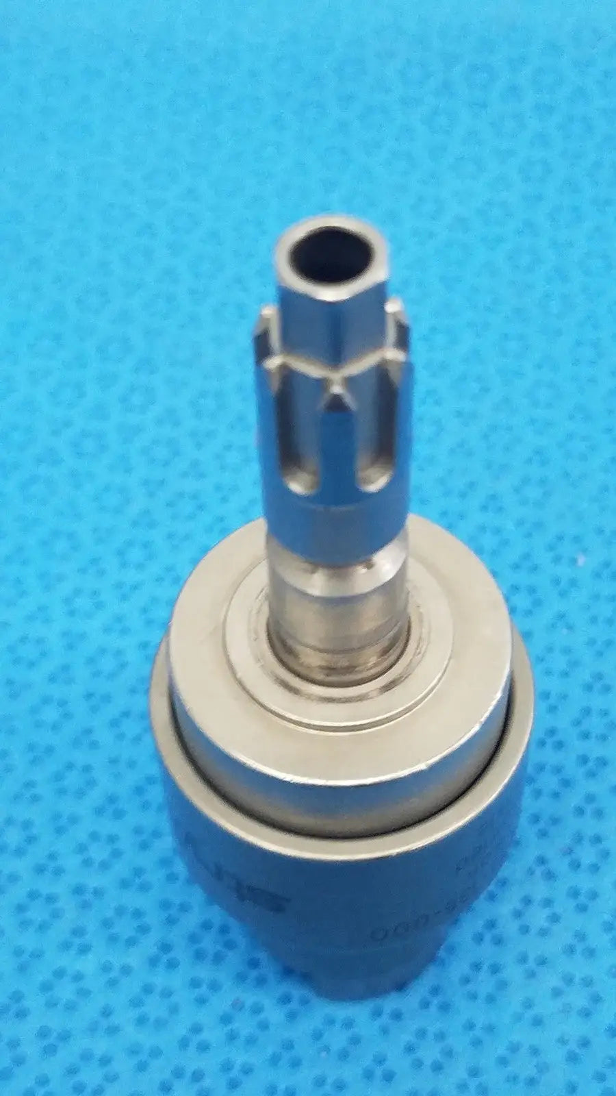 Silver-colored metal dental handpiece chuck with cylindrical shaft and gear-like protrusions for stryker hudson modified trinkle