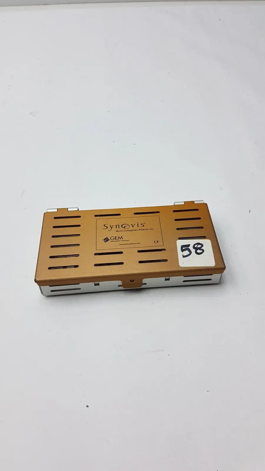Bronze-colored metal synovis gem precision instrument case with ventilation slits and white label number 58