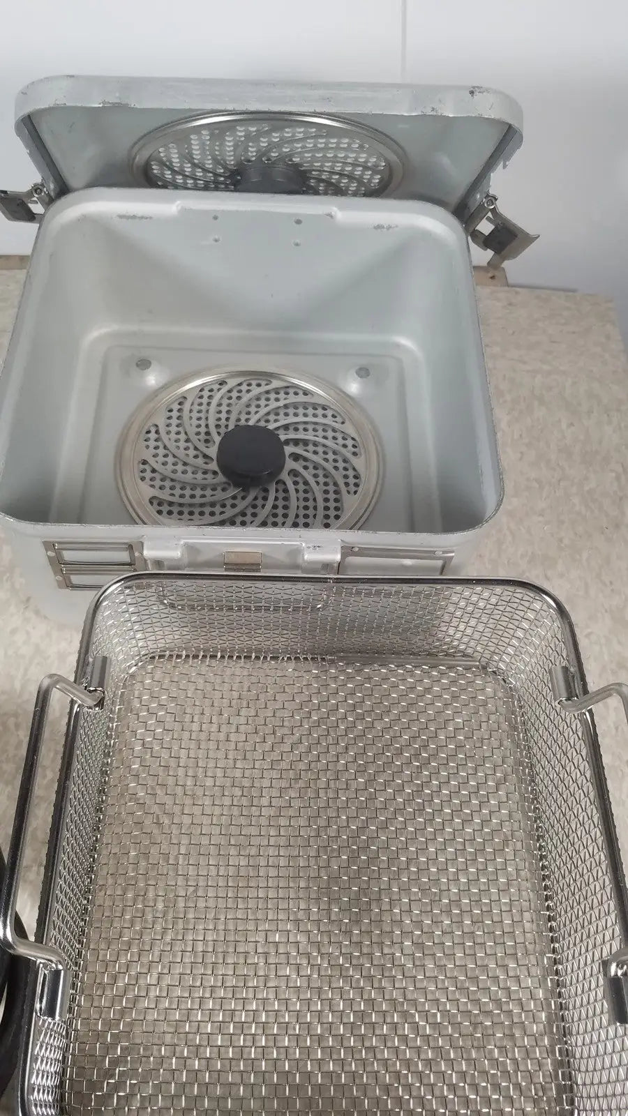Silver stainless steel deep fryer basket with mesh design and side handles from the case genuis serial no 9354 patent pending